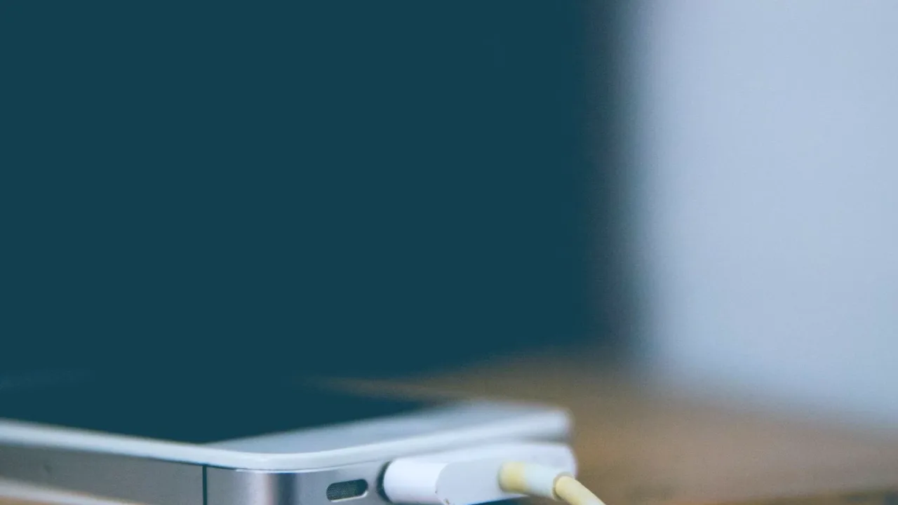 Ahşap masada şarj kablosuna takılı akıllı telefon